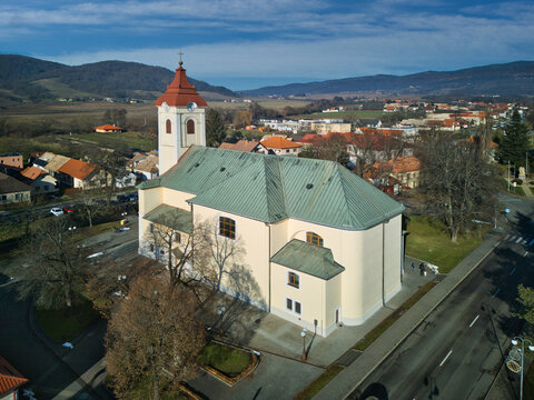 Aerial view of the majestic church with its red-capped tower piercing the skyline, amidst the sprawling townscape and distant mountains, Detva, Bansk&Atilde;&iexcl; Bystrica Region, Slovakia.