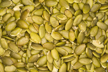 Heap of peeled pumpkin seeds, top view close-up