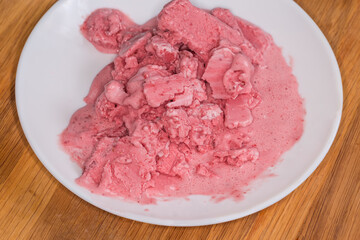 Partially melted strawberry filled ice cream on dish close-up