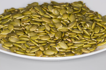 Heap of peeled pumpkin seeds, front view in selective focus
