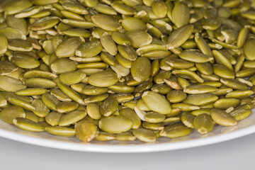 Heap of peeled pumpkin seeds, front view in selective focus
