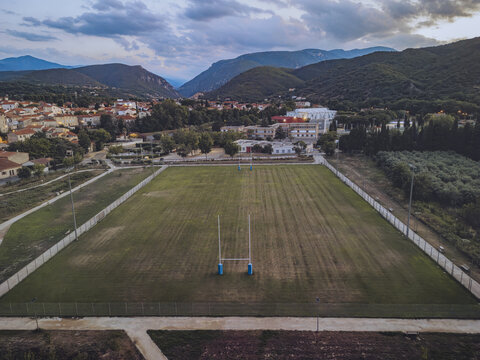 Aerial view of the rugby field bathed in the soft glow of twilight, framed by the distant, majestic mountains, Prades, Occitanie, France.