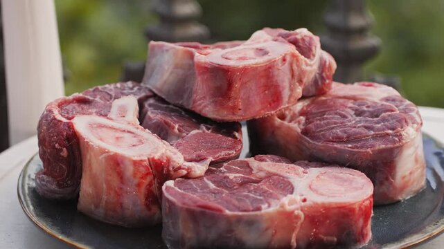 Fresh beef ossobuco steak with salt, spices and herbs on textured background, bones. 