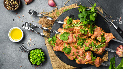 Raw pork kebab with cilantro on metal skewers. On a black slate plate. Top view.