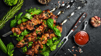 Delicious juicy skewers with pork meat grilling, grilled pork kebabs on a stone slate plate. Top view. On a dark textured background.