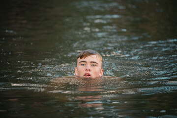 Fototapeta premium Teenage boy swimming in river on summer day