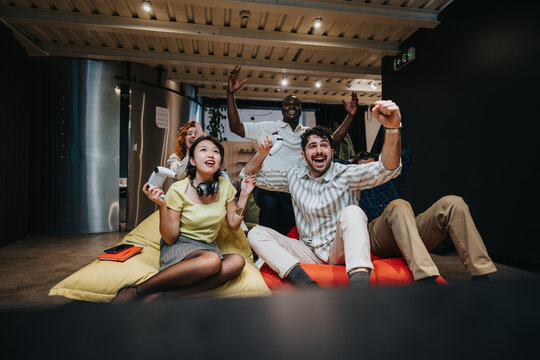 A diverse group of coworkers joyfully playing video games in a stylish workspace, displaying teamwork and relaxation, fostering connections during an engaging team-building session.