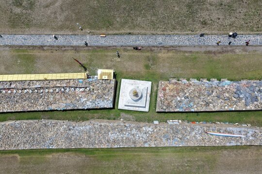 Aerial view of the ancient stone wall adorned with vibrant carvings and weathered textures, juxtaposed against the earthy tones of the surrounding landscape, Bage Mani Stone Wall, Sichuan, China.