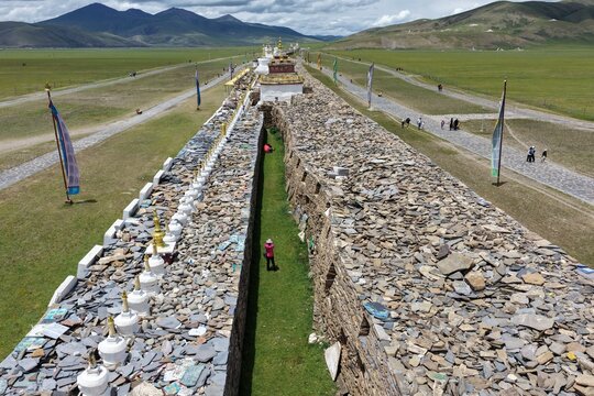 Aerial view of the expansive Bage Mani Stone Wall stretches through the vibrant green landscape under a vast sky, Bage Mani Stone Wall, Sichuan, China.