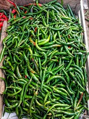 Fresh green chili peppers piled together, perfect for food background, spicy cuisine, agriculture, and organic vegetable market concepts.