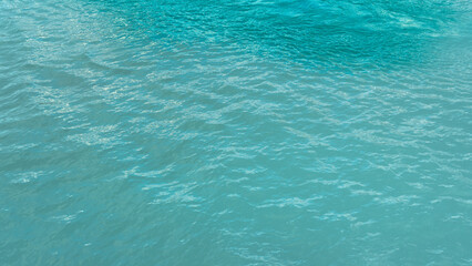 This image features the textured surface of the ocean in bright blue-green hues, reflecting sunlight with subtle waves.