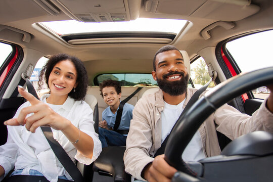 Happy woman pointing out something of interest during family car trip, boy observing from the back seat, encapsulating shared adventure - Powered by Adobe