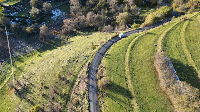 Aerial view of a winding road cutting through a landscape of verdant fields and scattered trees, Posof, Ardahan, T&Atilde;&frac14;rkiye.