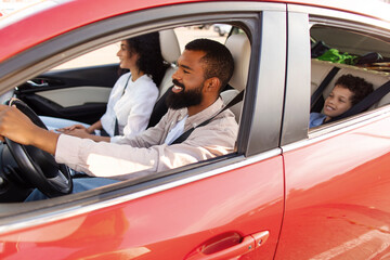 Family ride. Latin parents and preteen son sitting in car together, man on drivers seat, going together on trip, shot from outdoors