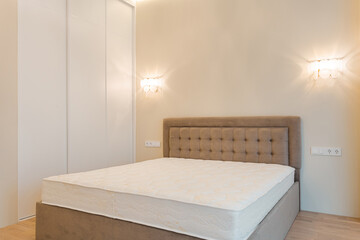 Modern bedroom with a minimalist design featuring a beige bed and soft lighting in a contemporary setting