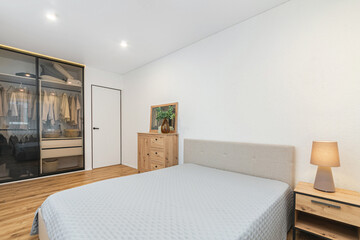 Modern bedroom interior featuring a cozy bed, wooden furniture, and ample storage in a serene environment