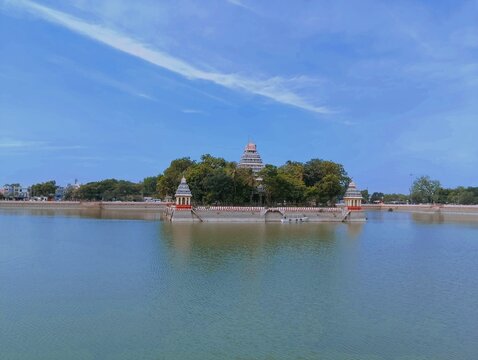 Aerial view of Vandiyur Mariamman Teppakulam in Madurai, with its serene temple island surrounded by calm waters, stands as a tranquil landmark under the bright blue sky