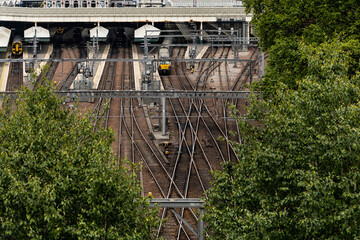 multiple rail tracks leading to a train station with a yellow train