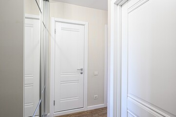 bright interior features two white doors and a mirrored closet. Walls are beige