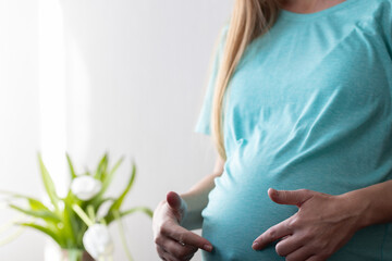Pregnant woman pointing with fingers on her big belly.