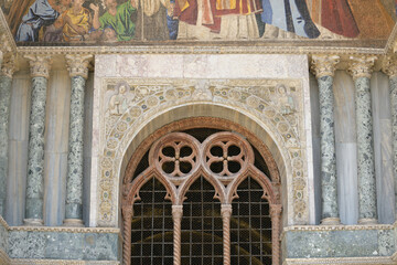 Arched window with twisted columns and sculpted marble decoration on the facade of St. Mark's Basilica (Basilica di San Marco), Venice, Italy.