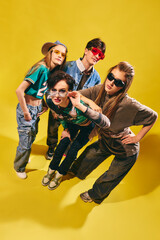 Stylish Gen Z friends in streetwear posing on bright yellow background with confident attitude....