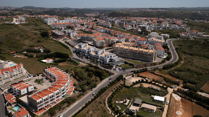 Aerial View of Coastal Town with Red-Tiled Roofs and Surrounding Countryside