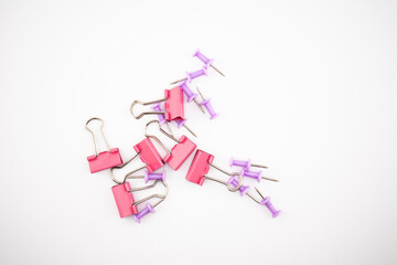 Red binder clips and purple push pins scattered on a white surface. A colorful flatlay of office supplies perfect for presentations, stationery themes, blogs, or productivity visuals.