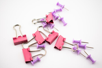 Red binder clips and purple push pins scattered on a white surface. A colorful flatlay of office supplies perfect for presentations, stationery themes, blogs, or productivity visuals.