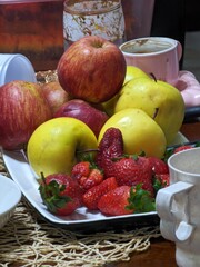 Fresh red and yellow apples with strawberries on a white plate for healthy eating