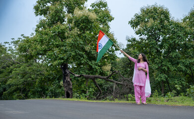 Cute little Indian girl holding, waving or running with Tricolor