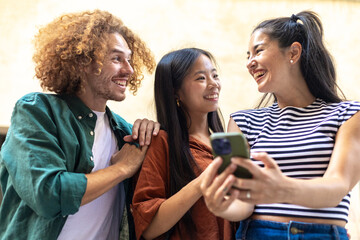 Group of young people sharing funny content on smartphone and laughing together