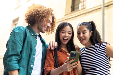 Group of happy young students watching funny content on mobile phone