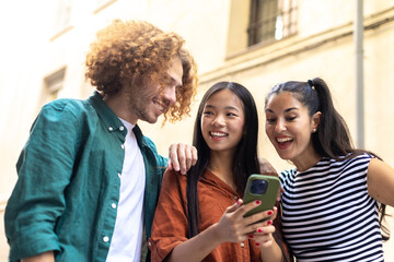 Happy students watching social media content on mobile phone