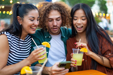 Friends enjoying drinks and social media at outdoor cafe