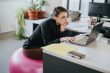 A focused professional working in a modern office environment on an exercise ball