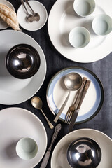Top view of an empty plates, bowls, glasses and cutlery placed on a black chalkboard background. Flat lay. Top view. Food concept.