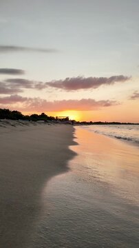 Golden sunset over Batticaloa Beach in Sri Lanka, with gentle ocean waves rolling onto the sandy shore and warm reflections on the water, creating a peaceful tropical seascape.
