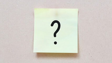 Yellow sticky note with a question mark on it. The note is placed on a white surface