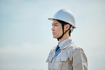 遠くを見つめる作業服姿の男性