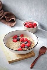 vegan healthy porridge bowl with fresh rasberries and blueberries on a white background  