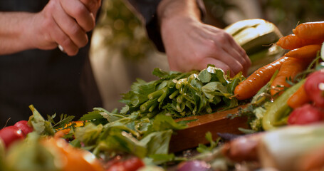Chef chopping fresh green vegetables on wooden cutting board