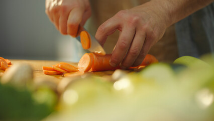 Chef slicing fresh carrots on wooden cutting board