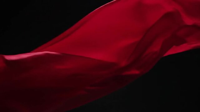 Close up of a flowing red fabric against a dark background creating a dramatic and elegant feel