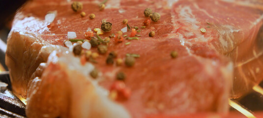Juicy t-bone steak grilling with salt, pepper and herbs