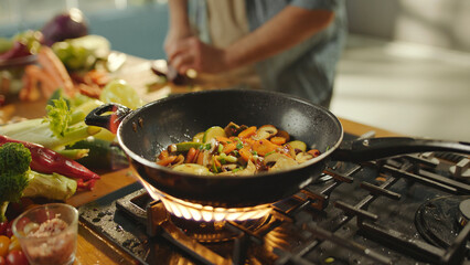 Chef cooking vegetables in wok on gas stove in kitchen