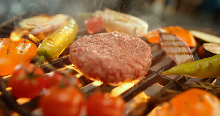 Chef grilling burger and vegetables on barbecue for summer party