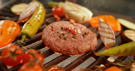 Chef grilling burger patty with vegetables on hot barbecue grill