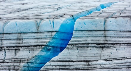 Obraz premium Deep blue crevasse cutting through the layered ice of a massive glacier.