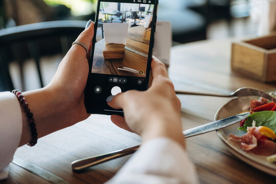 Scanning the QR code by smartphone. Close up view of teenage girl that is sitting in the cafe restaurant